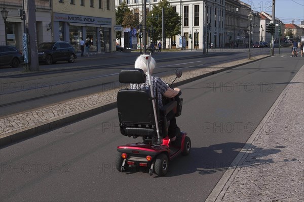 Older lady in a wheelchair on a bicycle path