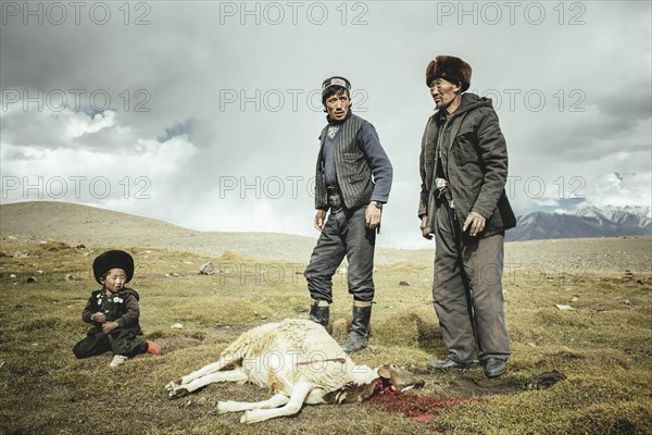 Two men and a boy after slaughtering a sheep