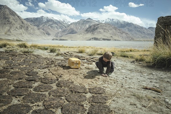 Boy plays next to cow dung flat cakes