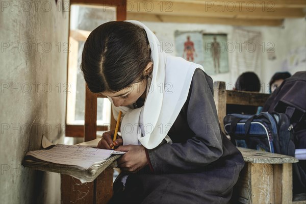 Girl writes in a notebook on a school desk