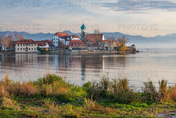 Peninsula with the parish church of St. George in front of the Alps in the evening sun