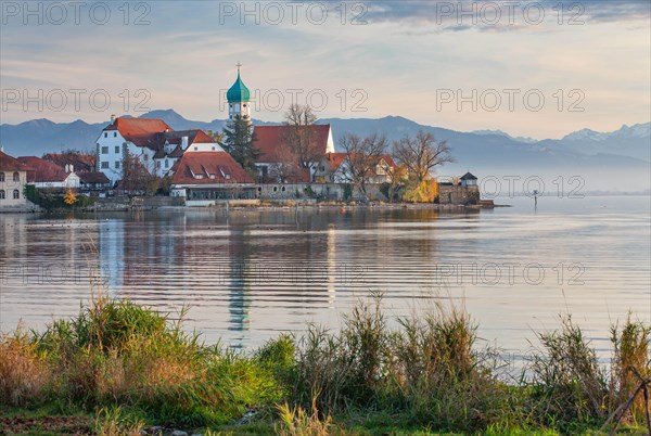 Peninsula with the parish church of St. George in front of the Alps in the evening sun