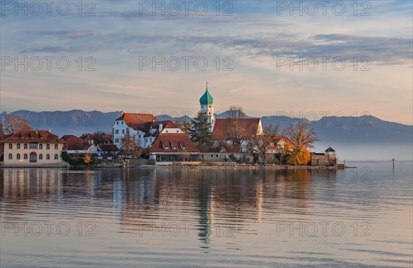 Peninsula with the parish church of St. George in front of the Alps in the evening sun