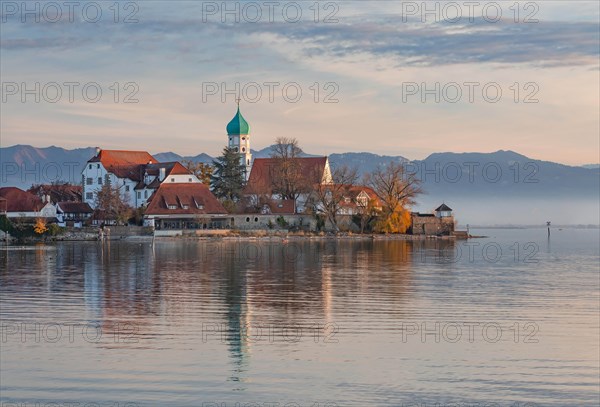 Peninsula with the parish church of St. George in front of the Alps in the evening sun