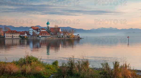 Peninsula with the parish church of St. George in front of the Alps in the evening sun