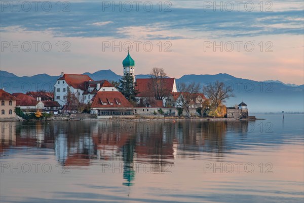 Peninsula with the parish church of St. George in front of the Alps in the evening sun