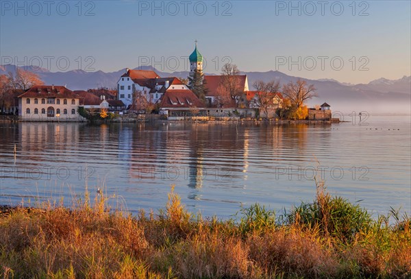 Peninsula with the parish church of St. George in front of the Alps in the evening sun