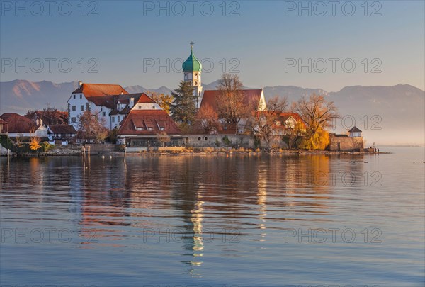 Peninsula with the parish church of St. George in front of the Alps in the evening sun