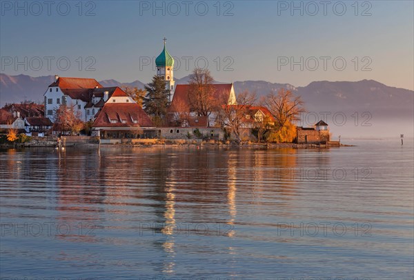 Peninsula with the parish church of St. George in front of the Alps in the evening sun