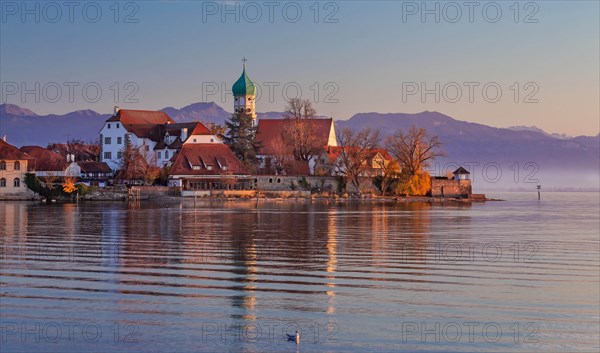 Peninsula with the parish church of St. George in front of the Alps in the evening sun