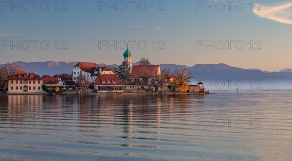 Peninsula with the parish church of St. George in front of the Alps in the evening sun