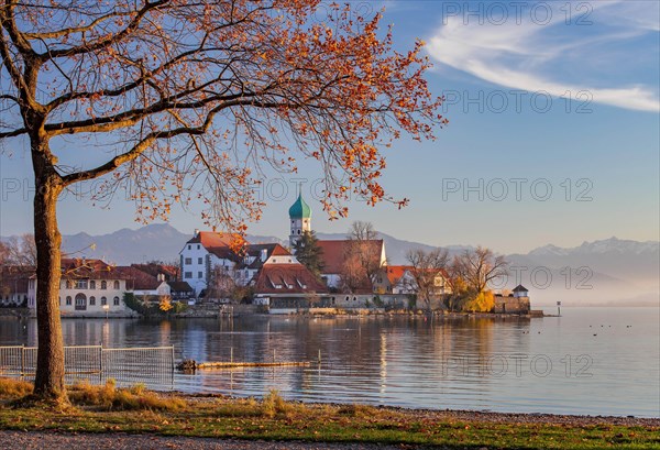 Peninsula with the parish church of St. George in front of the Alps in the evening sun