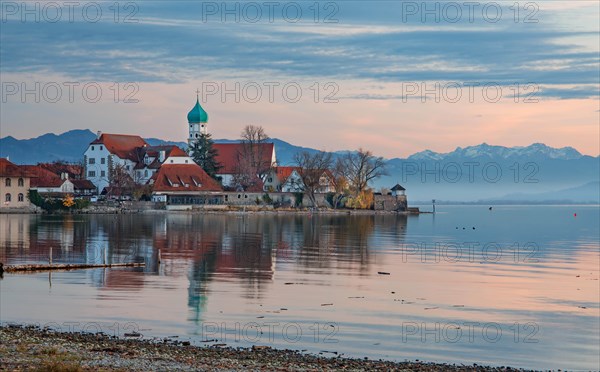 Peninsula with the parish church of St. George in front of the Alps in the evening sun