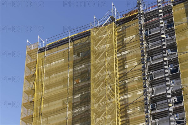 Facade with scaffolding and yellow cladding
