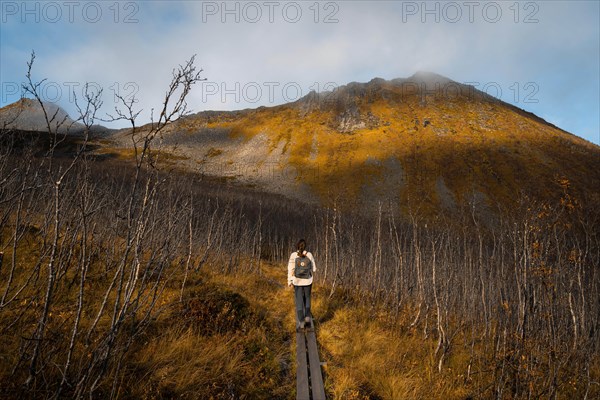 Woman hiking to Sega mountain in autumnal fjord landscape