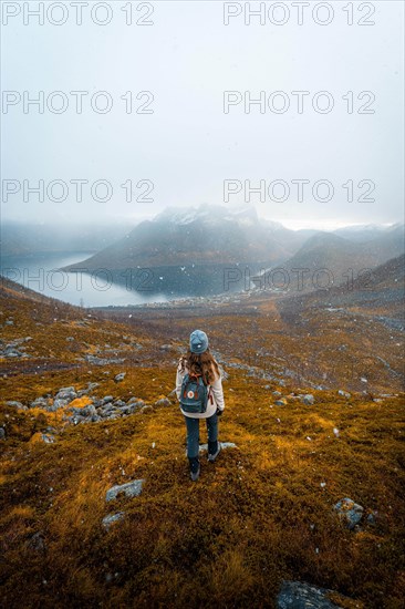 Woman looking at the village Fjordbotn and a prominent and pointed mountain