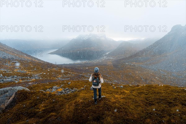 Woman looking at the village Fjordbotn and a prominent and pointed mountain