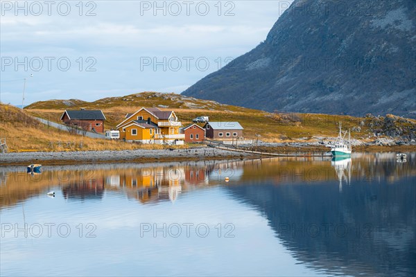 Colorful houses and sailboat mirrored in the lake with autumn vegetation