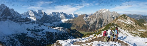 Three hikers on hiking trail with snow in autumn