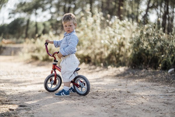 Cute toddler riding his balance bicycle on a dirt road