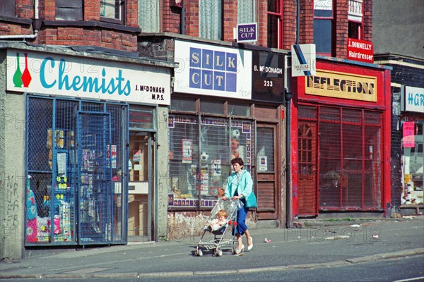 Woman with pram in front of barred shops