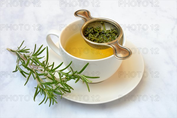 A cup of rosemary tea with tea strainer