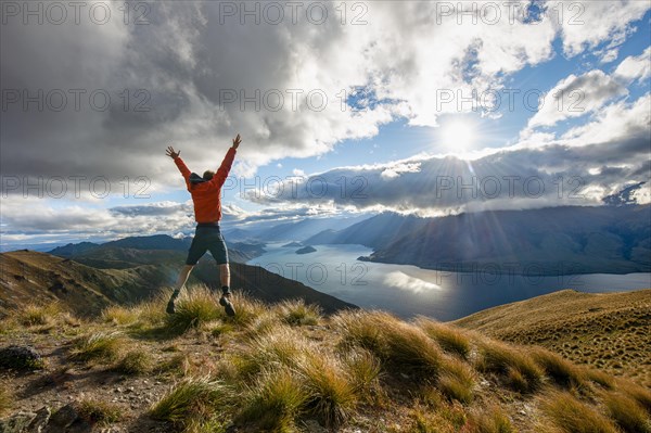Hiker stretches his arms in the air and takes a leap in the air