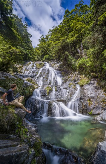 Young man sitting at a waterfall