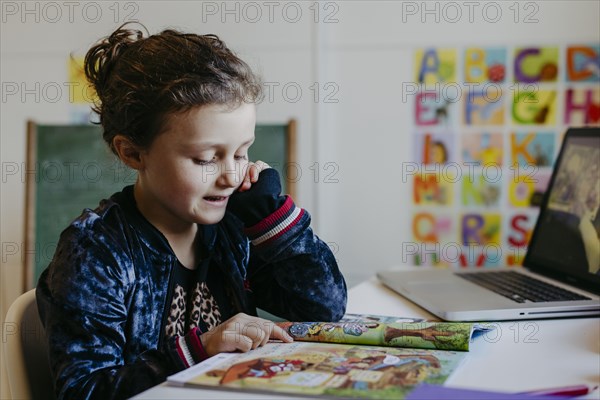 Little girl learning with reading book and laptop