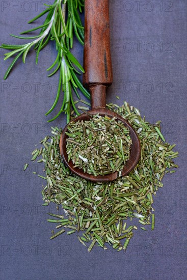 Dried and crushed rosemary in wooden spoon