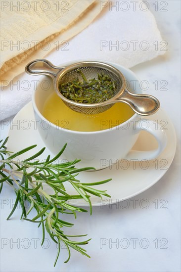 A cup of rosemary tea with tea strainer