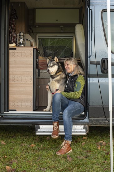 Wife and dog sitting in a camper. Camping. Luetzelsoon