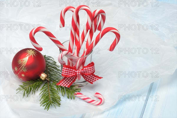 Candy canes in glass and Christmas tree ball with fir branch