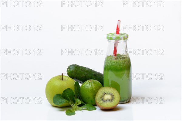 Green smoothie in glass with straw and fruit and vegetables