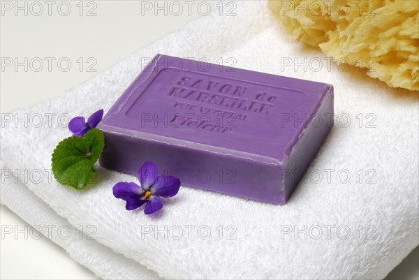 Violet soap and violet flowers on towel