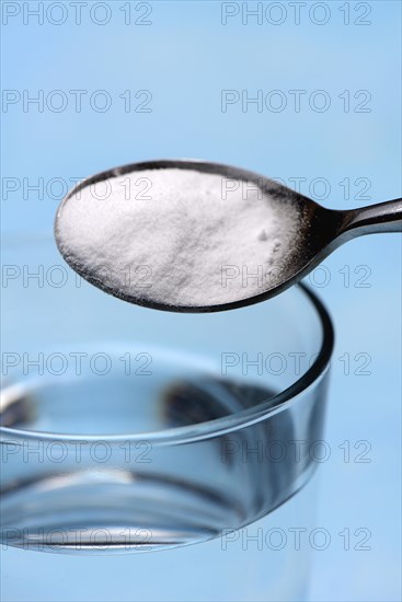 Spoon with baking soda and glass of water