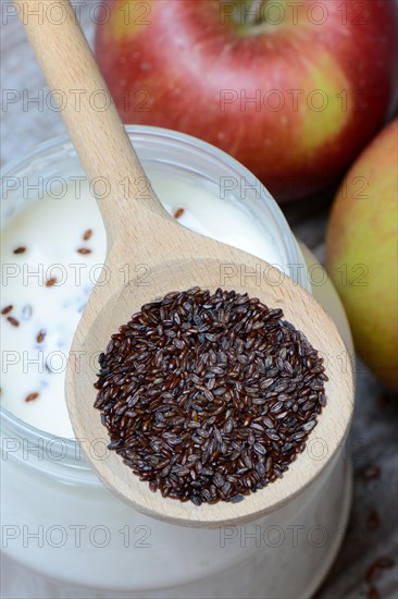 Psyllium plantain in cooking spoon on yoghurt glass and apples