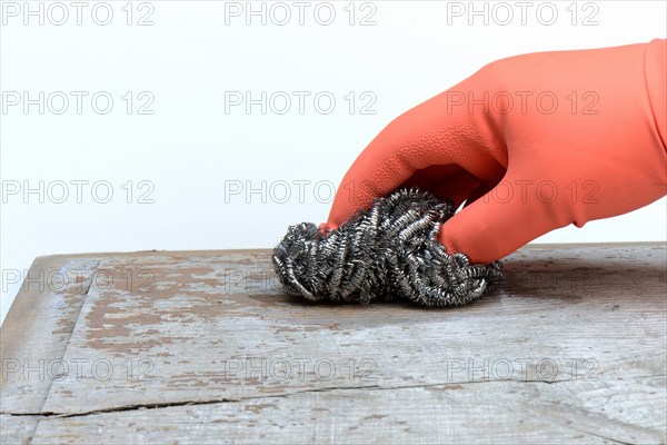 Hand with steel shavings cleans wooden board from paint residues