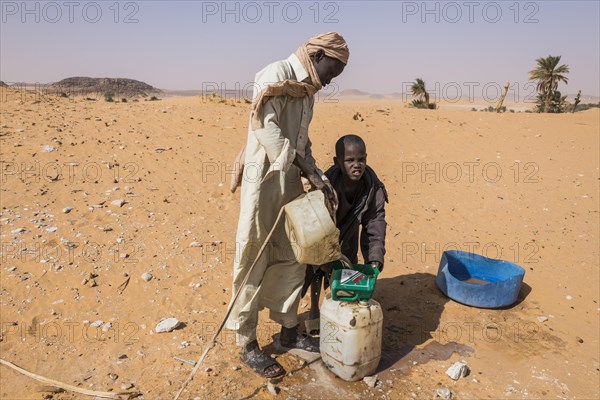 Local boys pulling out water out of a well in the desert