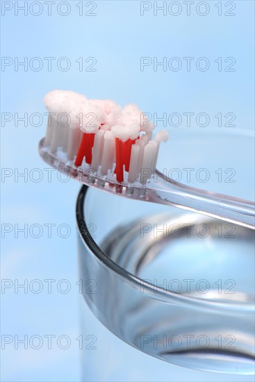 Sodium powder on toothbrush and glass with water