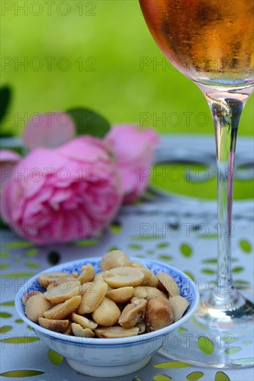 Glass of rose wine and small bowl with peanuts