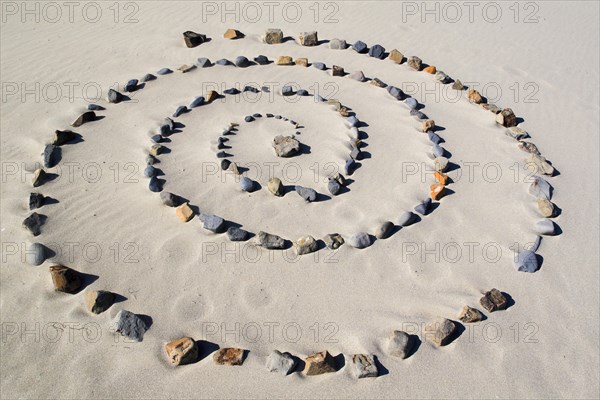 Spiral of stones on sandy beach