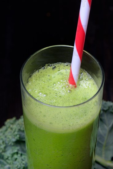 Kale smoothie in glass with drinking straw