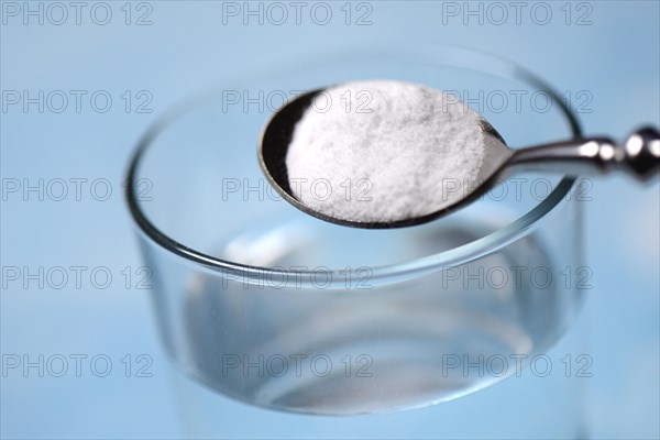 Spoon with baking soda and glass of water