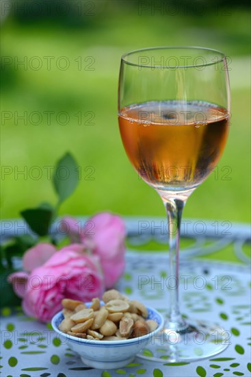 Glass of rose wine and small bowl with peanuts