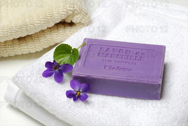 Violet soap and violet flowers on towel