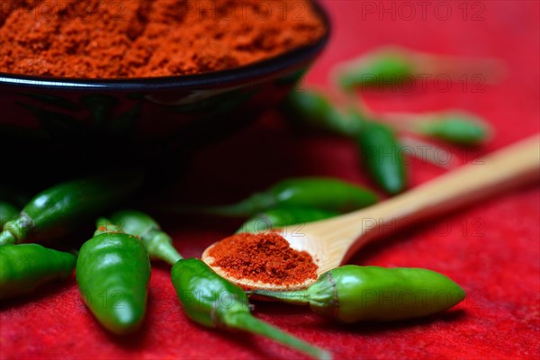 Chili powder in bowl and spoon and green chillies