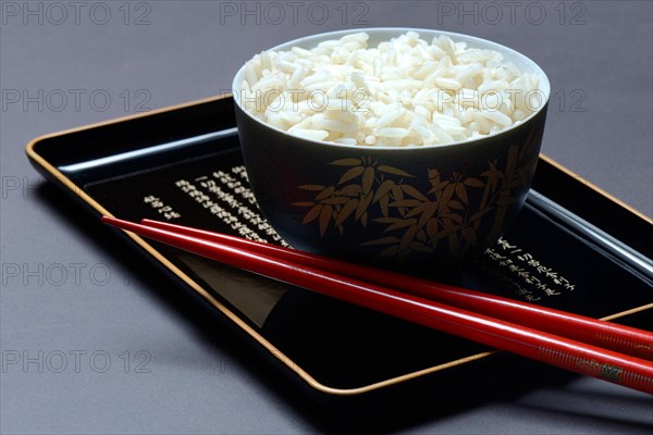 Boiled rice in bowl with chopsticks