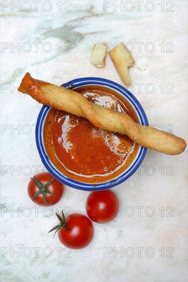 Tomato soup in cup with breadstick and tomatoes