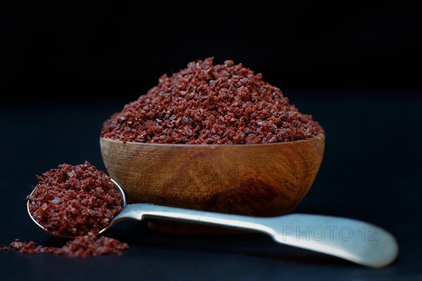 Sumac powder in wooden bowl and spoon